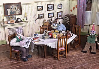 Models made by Aardman Animation animators of Wallace and Gromit with Norbot. The characters are sat around a wooden table in Wallace and Gromit's house.